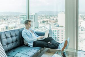 OnlineWorker - Mann im Apartment mit Laptop auf seinem Schoß